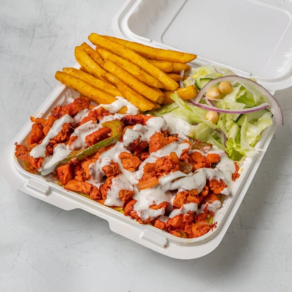 Halal Haven's chicken over rice with white sauce, fries, and a side salad in a takeout container.