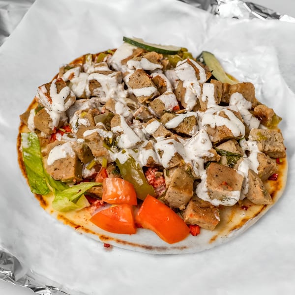 Halal Haven's gyro with meat, lettuce, tomatoes, and white sauce on pita bread.