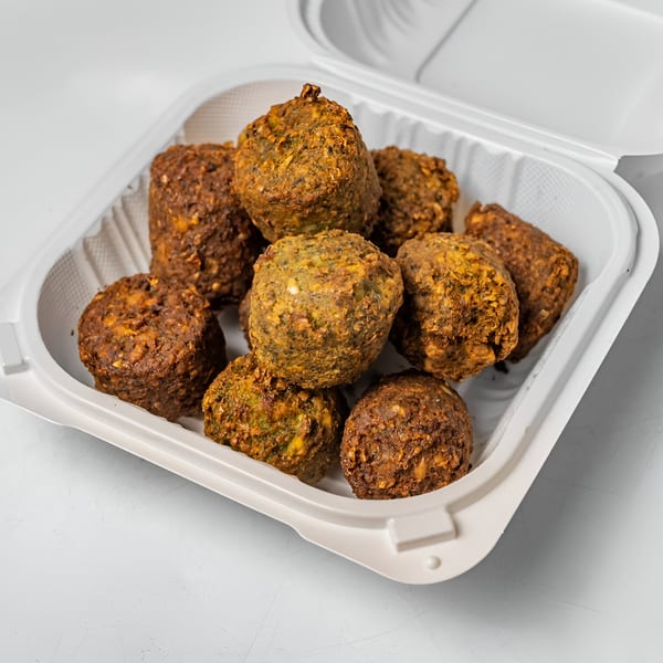 Halal Haven's crispy falafel balls, golden brown and green, in a white takeout container.