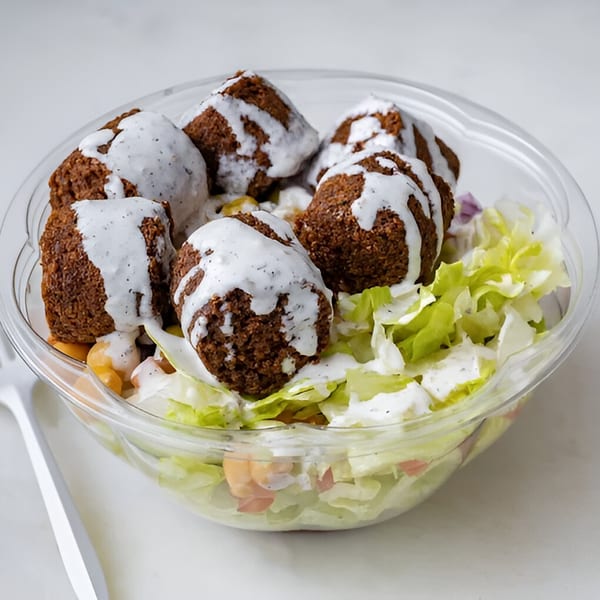 Halal Haven falafel with white sauce, lettuce, and chickpeas in a clear plastic bowl.